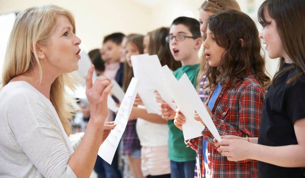 Teacher teach children how to sing properly.