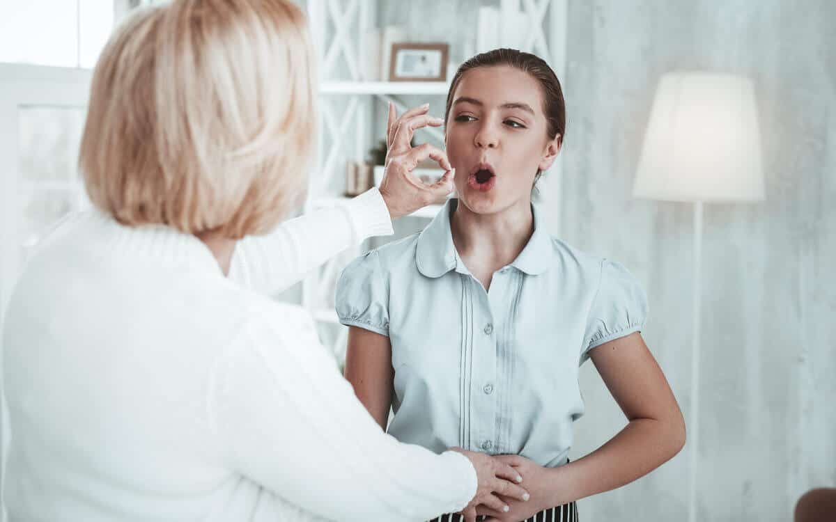 Vocal coach teaches student how to shape her vocal cords.